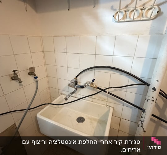 כיור עם ברזים וצינורות בחדר קטן
